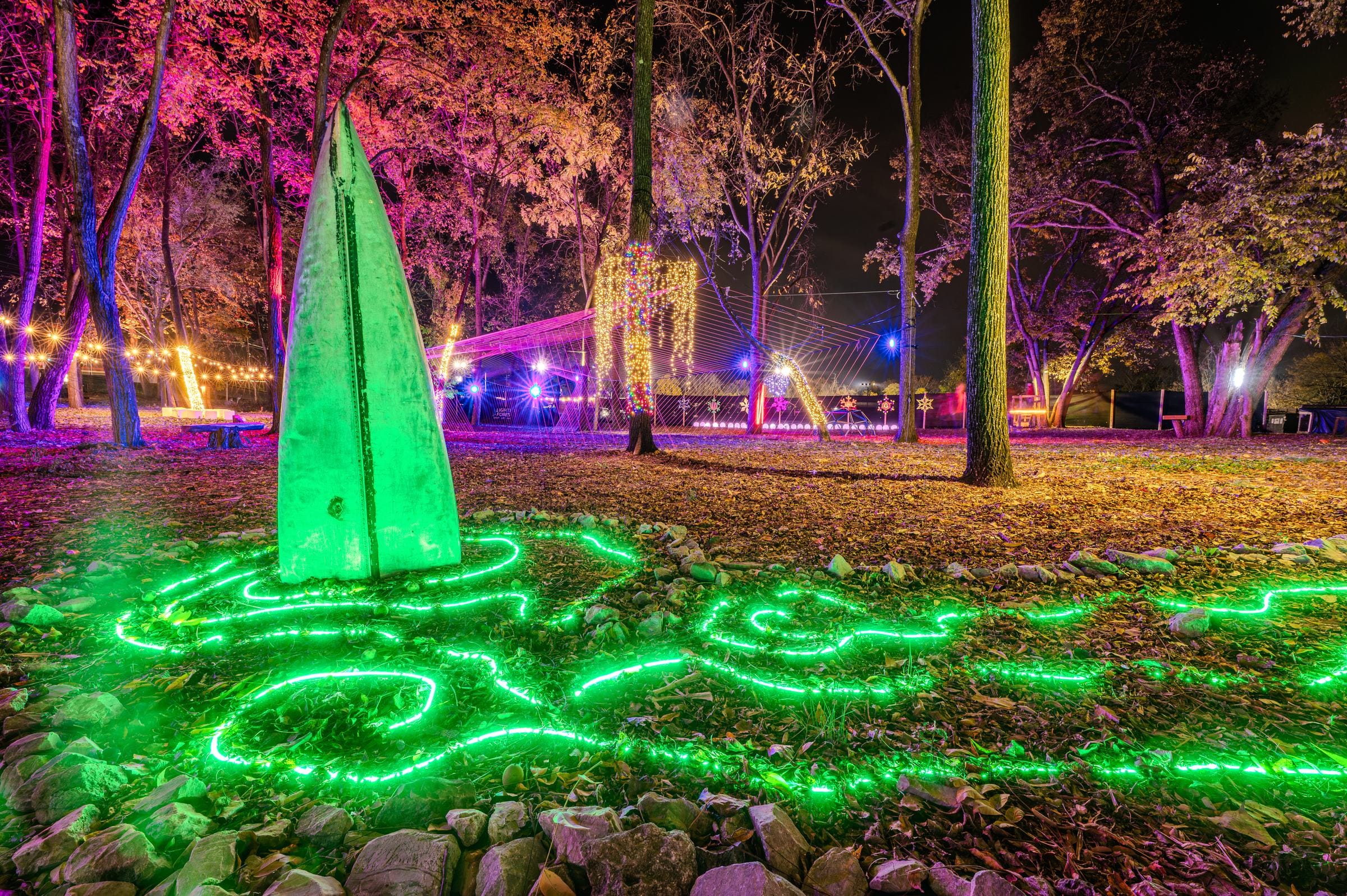 An upended canoe glowing green above a ring of green light in the woods