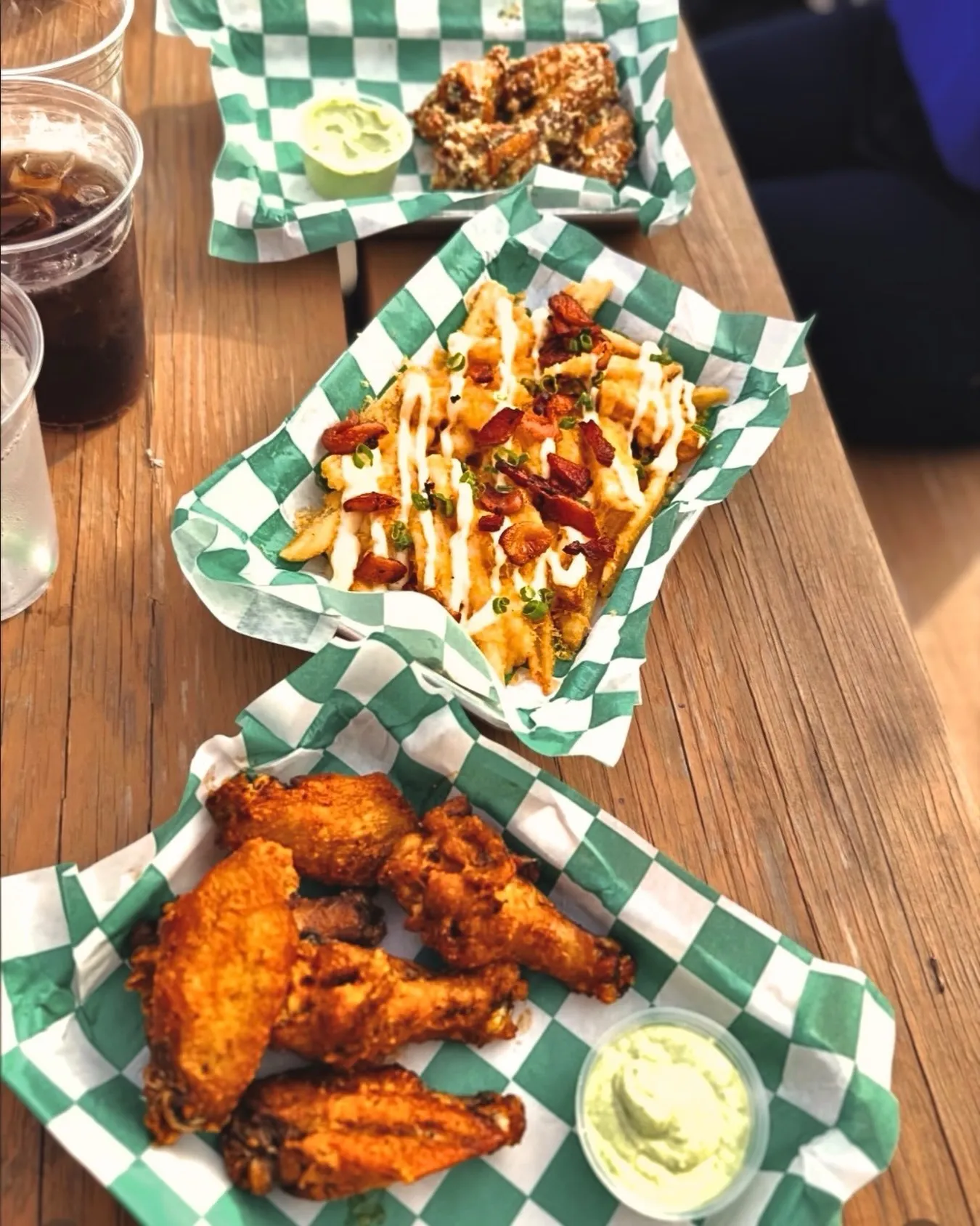 Loaded fries and house-smoked wings in green checkered baskets at The Acres